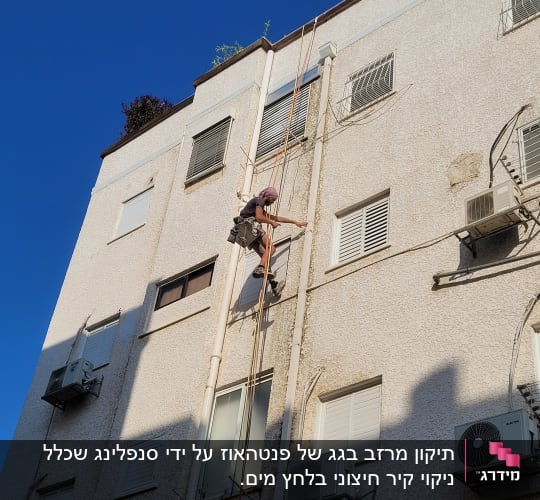 אדם מטפס על קיר בניין עם חבלים ורתמה
